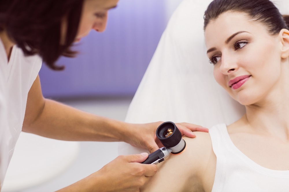 Dermatologist examining skin of patient with dermatoscope in clinic